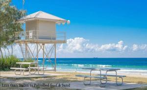 a lifeguard tower on the beach with two picnic tables at Shoreline Luxe - Refined Beachside Elegance with Spa in Caves Beach