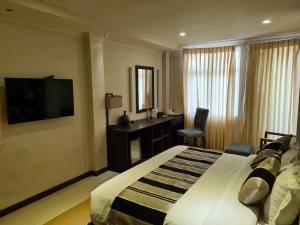 a bedroom with a bed and a desk and a television at Lagoon Lodge in Hithadhoo