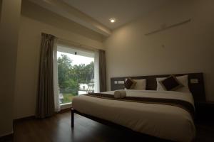 ein Schlafzimmer mit einem großen Bett mit Fenster in der Unterkunft Sreeja Myst in Athirappilly