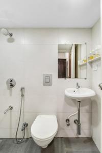 a white bathroom with a toilet and a sink at Maven 1BHK Khar W by The Bombay Home Company in Mumbai