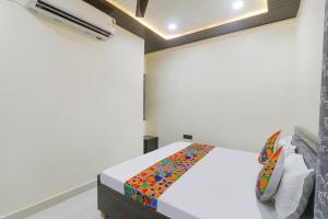 una camera da letto con un letto bianco e una coperta colorata di FabExpress Awadh Inn - 400m from Shri Ram Janam Bhumi a Ayodhya