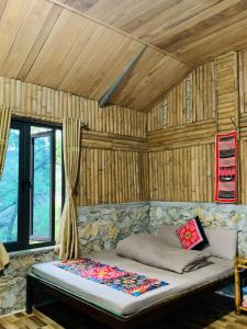 a bed in a room with a wooden ceiling at Y Sao Homestay in Hòa Bình