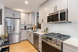 Una cocina con gabinetes blancos y electrodomésticos de acero inoxidable. en NEW Townhome in the Heart of Seattle, en Seattle 26 fotos más