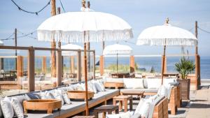 a patio with white couches and tables and umbrellas at Oak & Beam Atelier in Haarlem