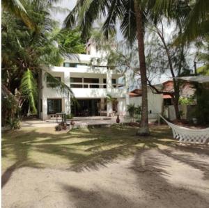 a house with palm trees and a hammock in a yard at Oasis em Praia Azul in Pitimbu