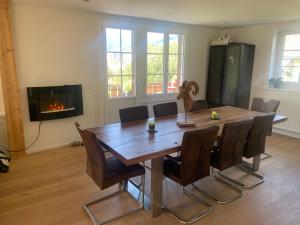 a dining room with a wooden table and a fireplace at Chalet l'Ermitage in Tavannes