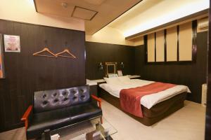 a hotel room with a bed and a leather chair at ホテルロコズマウイ in Honjo