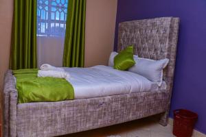 a bedroom with a bed with a chair with green curtains at Memento airb&bs apartments in Nakuru