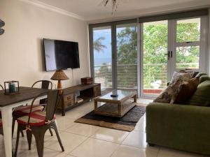 a living room with a couch and a table with a television at Cozy, 2 bedroom beachfront apartment in Ballito