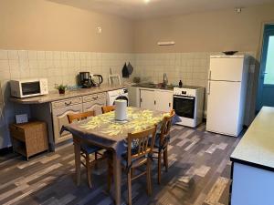 eine Küche mit einem Tisch und Stühlen sowie einem weißen Kühlschrank in der Unterkunft Le Gîte du Chat Gru in Saulxures-sur-Moselotte + 6 Fotos