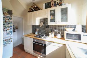 a kitchen with white cabinets and a stove top oven at Dweller Holiday Homes in Headingley