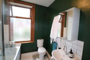 a green bathroom with a toilet and a sink at Dweller Holiday Homes in Headingley +6 photos