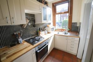 a kitchen with white cabinets and a stove top oven at Dweller Holiday Homes in Headingley