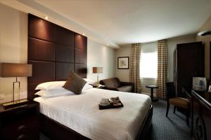 a hotel room with a large bed and a chair at Stamford Bridge Hotel London in London