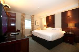 a hotel room with a bed and a flat screen tv at Stamford Bridge Hotel London in London