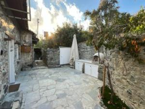 un patio de piedra con sombrilla y pared de piedra en Finikous Cottage House-Agros, en Agros