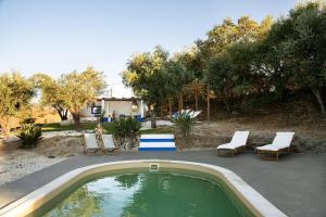 a swimming pool with two chairs and a person sitting in a yard at Monte Frecae in Alandroal