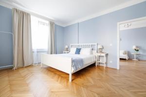 a bedroom with a white bed and a wooden floor at Papageno Apartments in Vienna +34 photos
