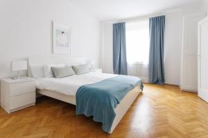 a white bedroom with a bed and a window at Papageno Apartments in Vienna