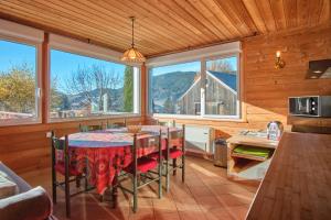 a dining room with a table and some windows at La Croix Du Sud in Villard-de-Lans
