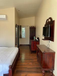 una camera da letto con un letto e una TV a schermo piatto di Vrindavan Greens Resort a Udaipur