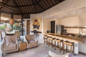 a kitchen with a bar with chairs and a table at Sandi Kala Villas in Kerobokan