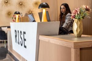 a woman sitting at a desk with a free sign at Rise Urban Art Hotel in Larnaca
