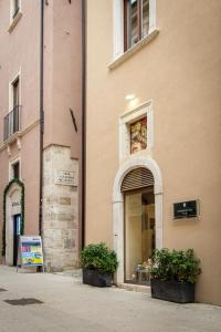 a store with two plants in front of a building at Le tre Spighe - Affitti Brevi Italia in LʼAquila