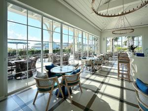 a restaurant with tables and chairs and windows at JOYY Villa 4PN-3WC-5 giường NovaWorld Phan Thiết in Bình Tú