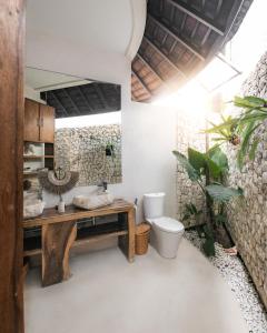 a bathroom with a toilet and a wooden table at Sandi Kala Villas in Kerobokan +41 photos