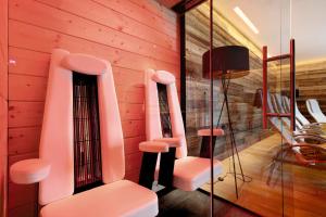 um quarto com cadeiras cor-de-rosa e uma parede de vidro em K Lodge Mountain em Valdaora