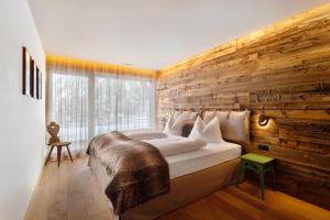 um quarto com uma cama grande com uma parede de madeira em K Lodge Mountain em Valdaora