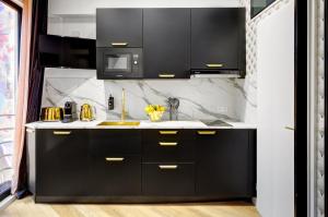 Una cocina con gabinetes negros y un fregadero. en 214 Suite Vuitton - Superb Apartment in Paris, en París