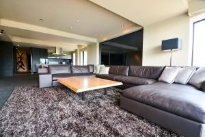 a living room with a leather couch and a coffee table at MUSE Niseko in Niseko