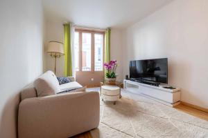 a living room with a couch and a flat screen tv at Maison des orchidées in Montélimar