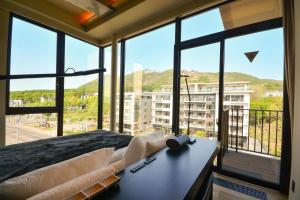 a room with a bed and large windows with a view at MUSE Niseko in Kutchan