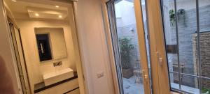 a bathroom with a glass door with a sink and a mirror at Trastevere incantevole con patio esterno privato in Rome +32 photos