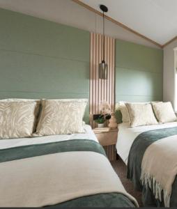 deux lits dans une chambre aux murs verts dans l'établissement LODGE SEA VIEW On the beach signature gold Hafan y Mor North Wales LL53 6HX, à Chwilog