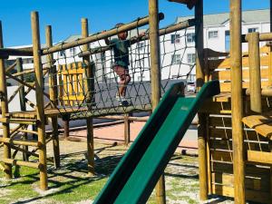 ケープタウンにあるBig Bay Beach Clubの遊び場の滑り台の少年