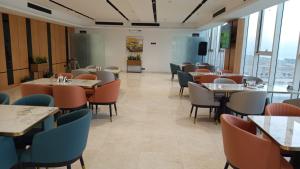 a dining room with tables and chairs and windows at فندق مورا - Mora hotel in Al Khobar