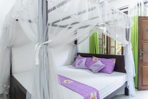 a bed with purple pillows and a canopy at DKC Apartment in Ahangama