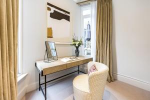Un escritorio y una silla en una habitación con ventana. en Buckingham & Lloyds Knightsbridge, en Londres