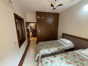a bedroom with two beds and a ceiling fan at Arcade Serenity Suites in Chikmagalūr