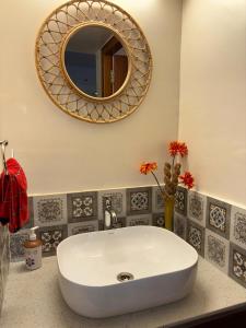a bathroom with a white sink and a mirror at Arcade Serenity Suites in Chikmagalūr