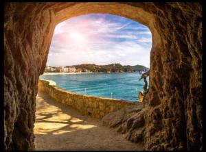 a view of the ocean through a stone archway at Parrot’s House in Lloret de Mar