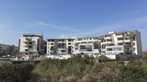 duży biały apartamentowiec na plaży w obiekcie SUNSET Joli T2 vue mer piscine SUNSET Cap d'Agde w Cap d'Agde