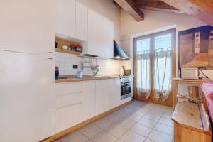 a kitchen with white cabinets and a large window at Appartamento Carla, Strembo in Strembo
