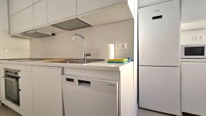 a white kitchen with a sink and a refrigerator at Aguaviva apartment in Callao Salvaje +50 photos