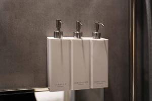 two white soap dispensers on a wall in a bathroom at Real Life IIDABASHI in Tokyo +113 photos