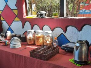 a table with jars of food and plates on it at Shik Shack Backpackers in Guernsey Nature Reserve